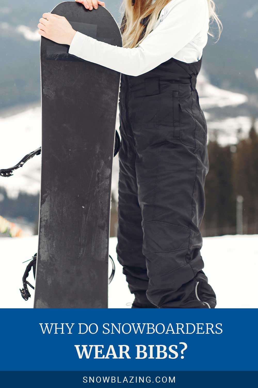 Lady wearing black snowboarding bib holding a snowboard.